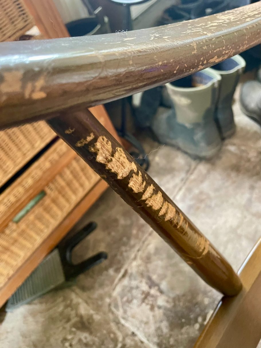 Damage to the arm A worn wooden surface with scratches, near rubber boots and woven storage.