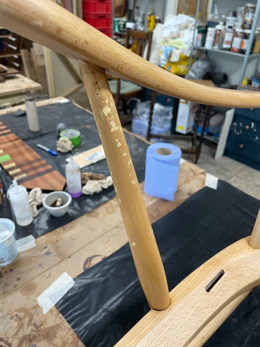 Filling the arm damage Close-up of a wooden furniture leg with a worn finish, surrounded by tools and materials.