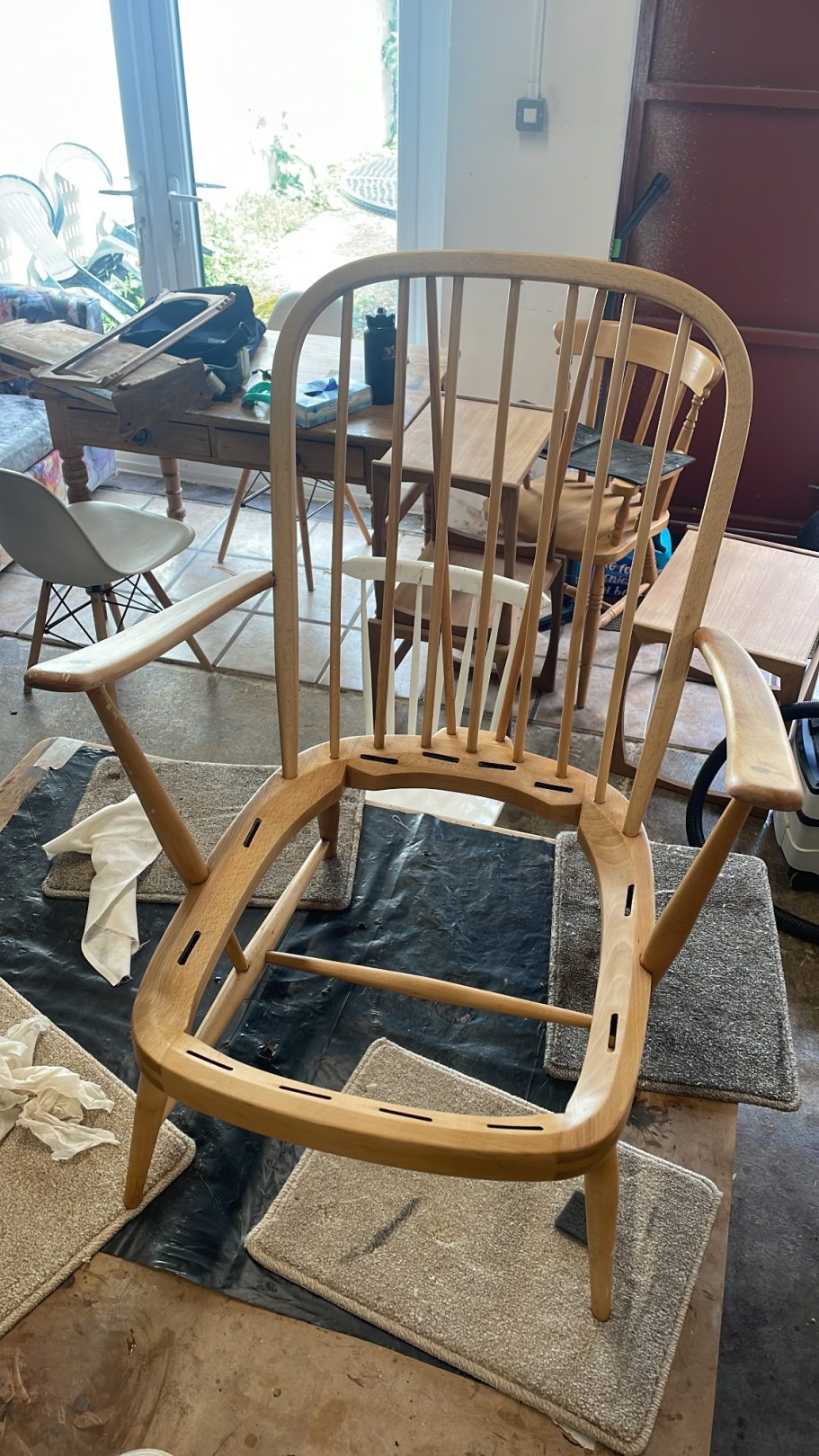 The chair is oiled Wooden chair frame with a curved backrest, unfinished and placed on a floor.