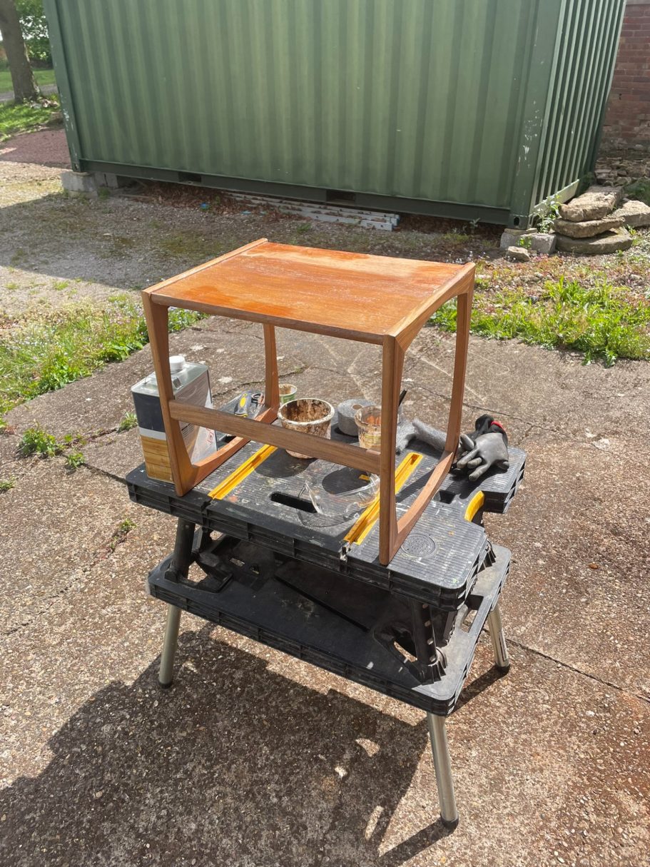 Stripping the finish A wooden frame atop a workbench with tools and equipment visible.