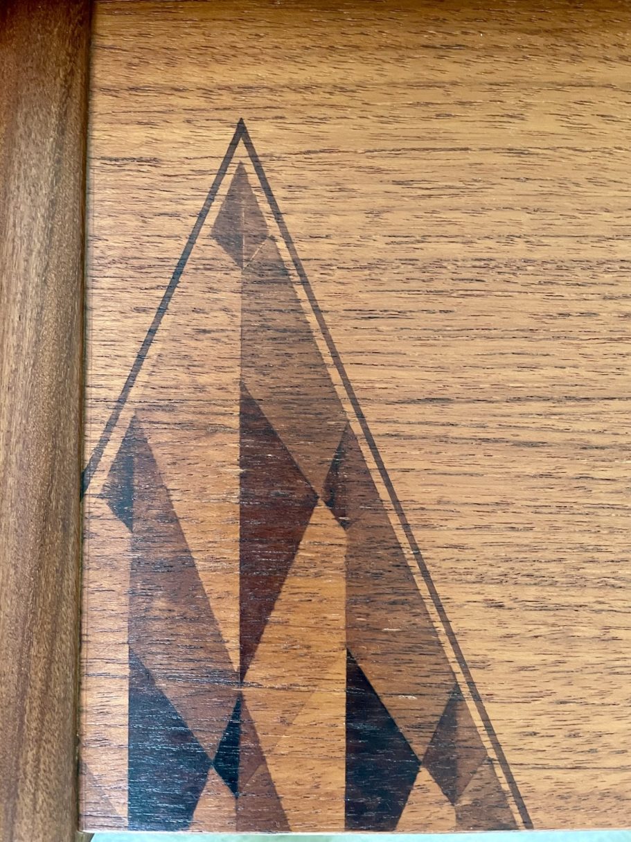Stain Design Geometric wooden inlay featuring a triangular design in brown and black shades.