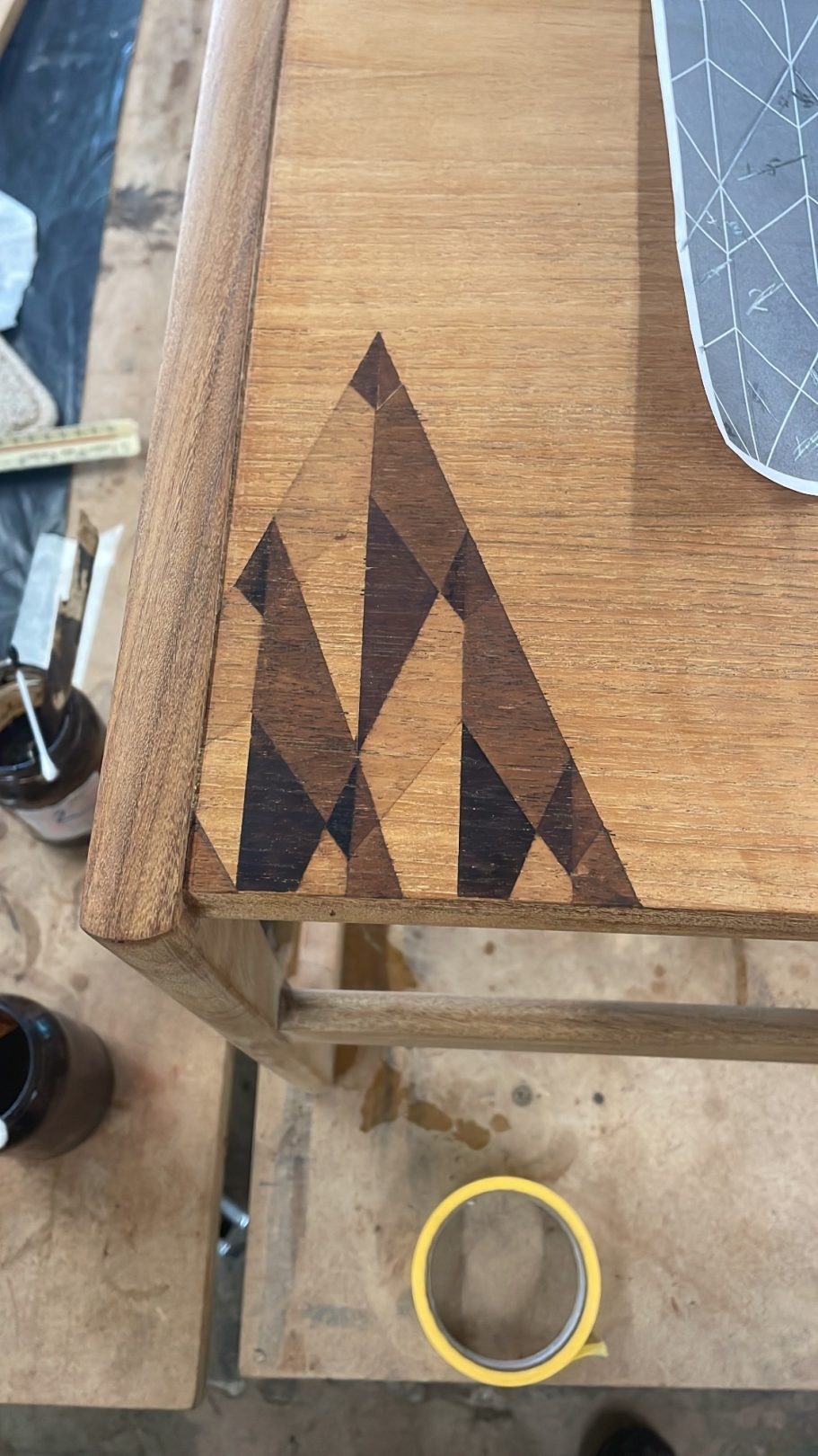 Part way through the design Wooden tabletop featuring a geometric inlay design with dark and light wood tones.