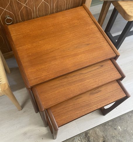 Wooden side table with three sliding drawers and a warm finish.