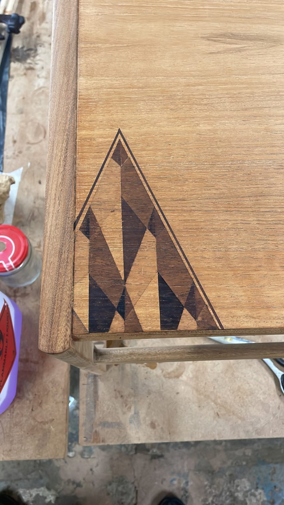 Finished Design Wooden surface featuring a geometric inlay design with triangular patterns.
